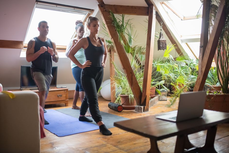 Group of adults participating in a fitness session in a cozy loft apartment with natural light.