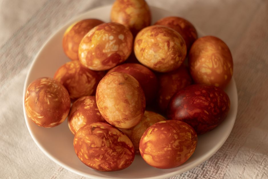 Close-up of marbled Easter eggs in a white bowl, featuring warm earthy tones.