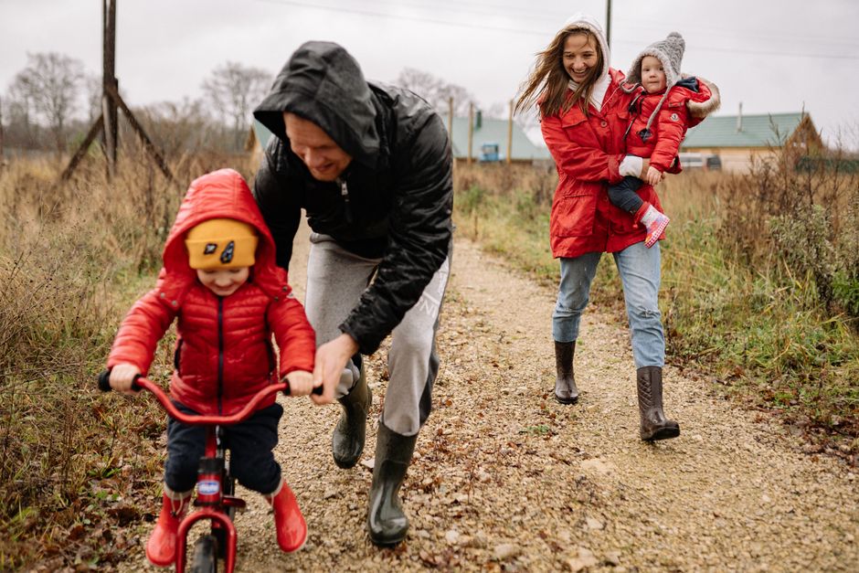 Family enjoying a joyful autumn walk along a rustic dirt road in vibrant outfits.