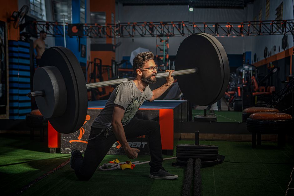 A bearded man squats with a barbell in a gym, showcasing strength and focus.