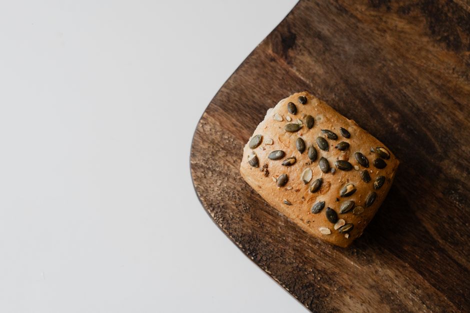 A loaf of seeded whole grain bread sits on a rustic wooden board with ample copy space.