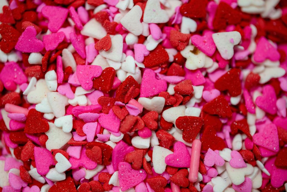 Bright close-up of heart-shaped candy sprinkles in red, pink, and white hues.