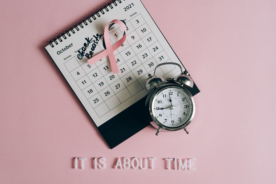 Calendar with pink ribbon, an alarm clock, and the text
