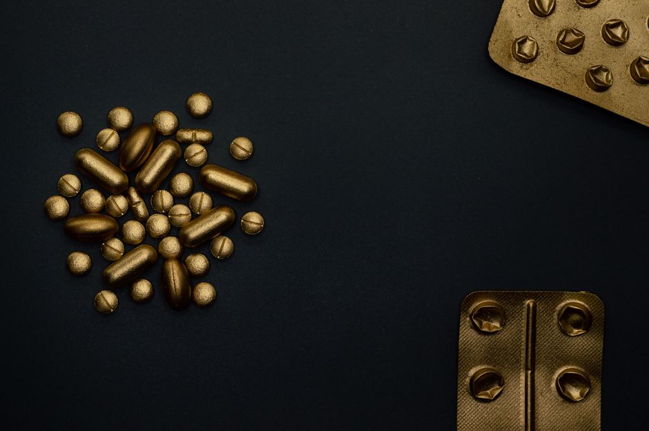 A conceptual image of golden pills and blisters on a dark background, symbolizing modern medicine.