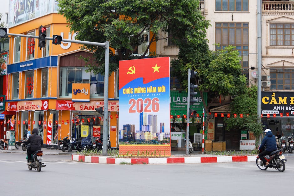 Vibrant Hà Nội street scene featuring a New Year 2026 billboard, motorcycles, and colorful shops.
