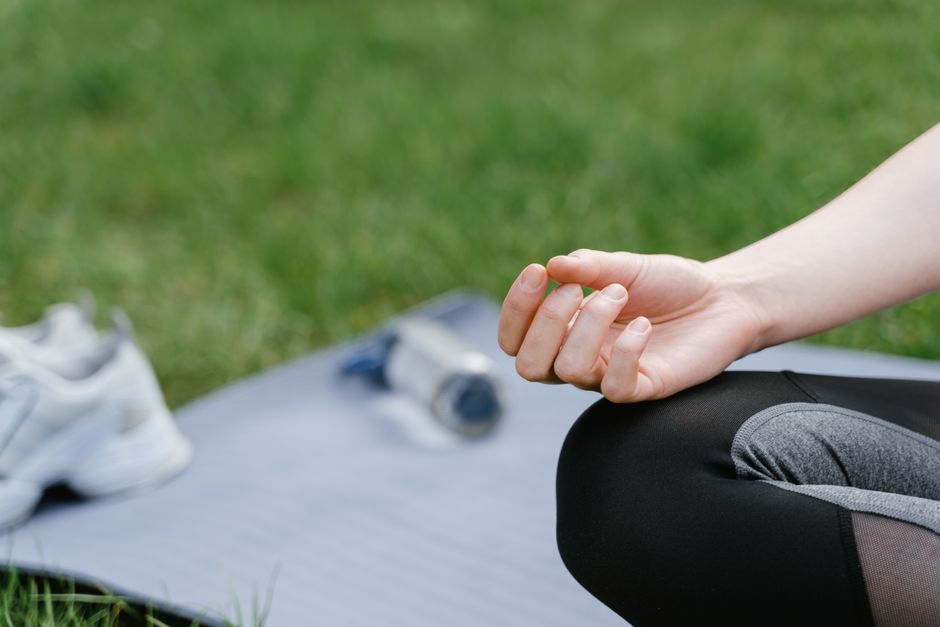 Close-up of a woman meditating outdoors on a mat. Focus on tranquility and mindfulness.