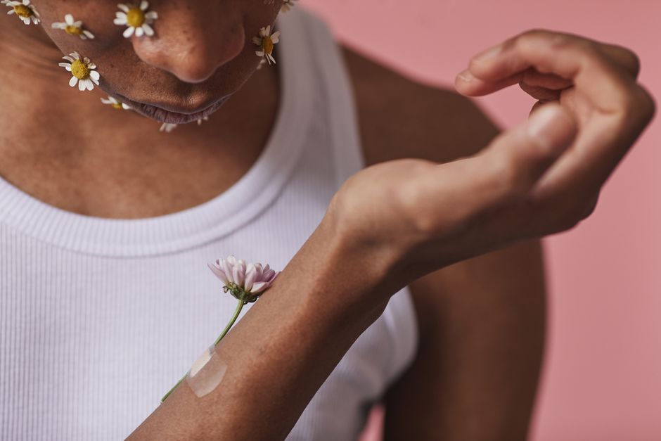 Artistic portrait featuring daisies on a man’s face and a floral arm detail.