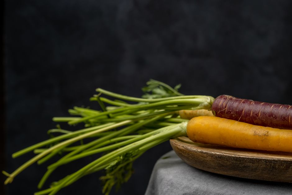 Close-up of colorful carrots on a wooden platter, showcasing fresh produce.