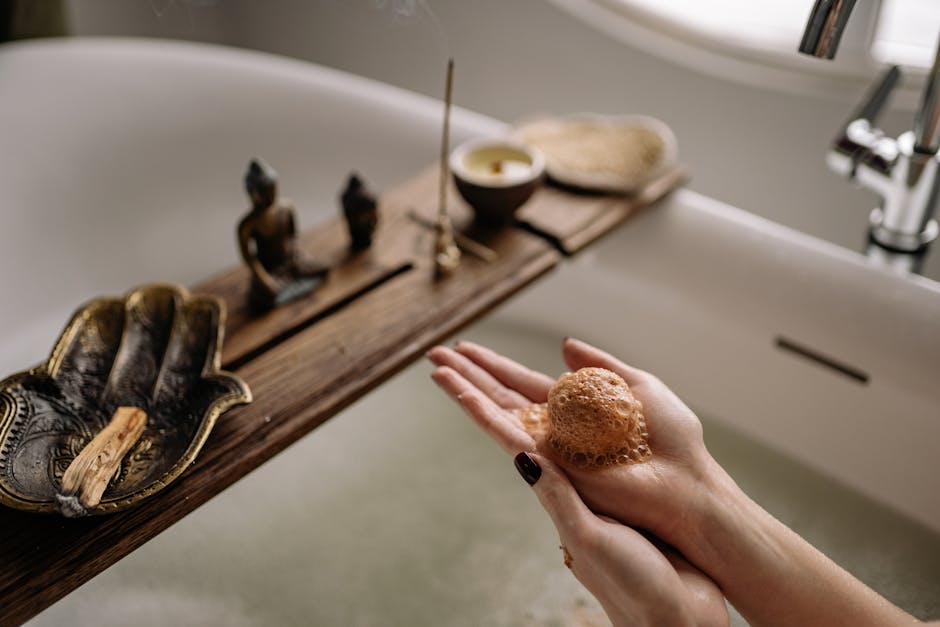 Hands holding a bubbly bath bomb in a peaceful setup with incense and candles.