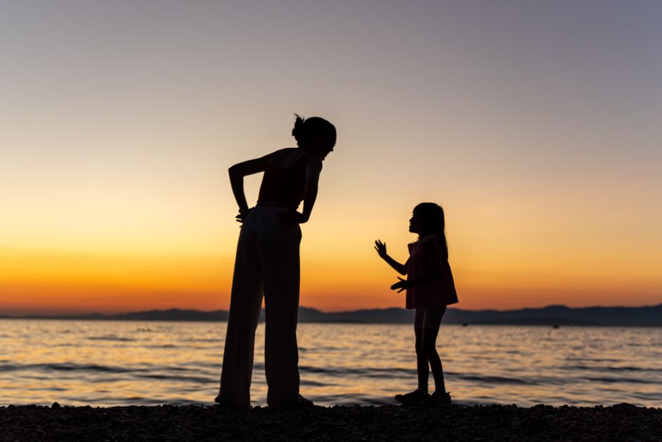 A beautiful silhouette of a mother and child on a beach during sunset, capturing a serene moment.