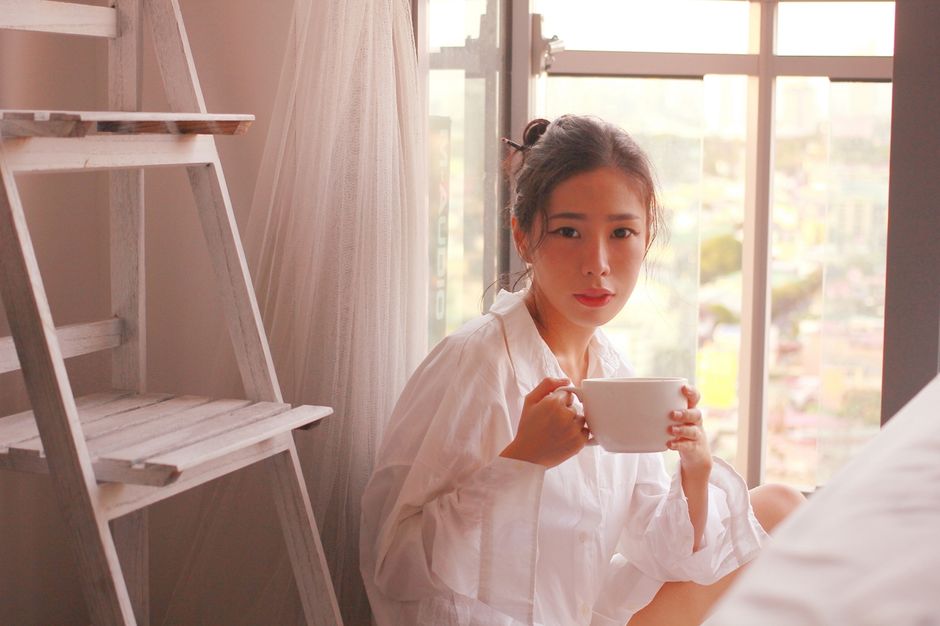Woman with a warm drink by a bright window in the morning